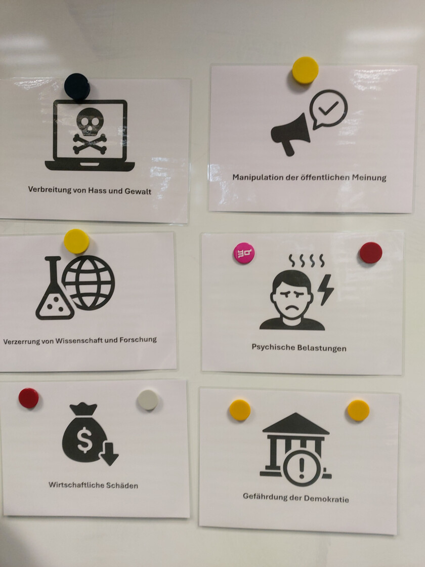 Mehrer laminierte Zettel hängen an einer Magnettafel. Darauf stehen die Gefahren von Fake News.